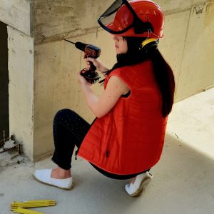 a woman sitting on the ground holding a drill